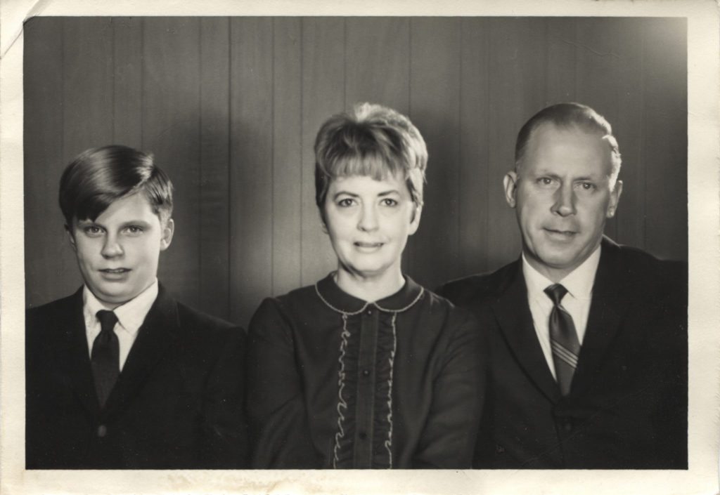 1950s era family photo of a son, mother, and father in formal wear. 